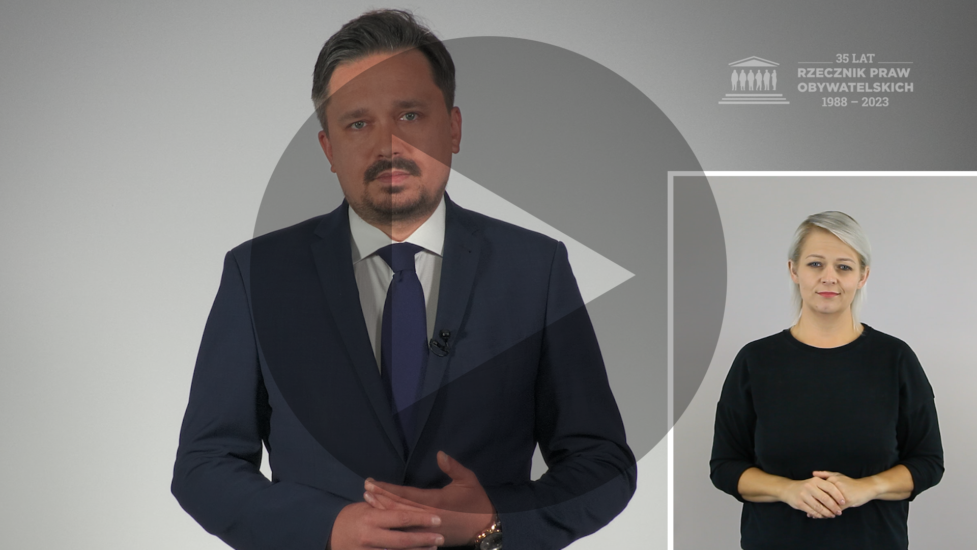 Kadr z nagrania przedstawiający RPO Marcina Wiącka i osobę migającą Polskim Językiem Migowym z naniesionym symbolem odtwarzania wideo - trójkątem w kole