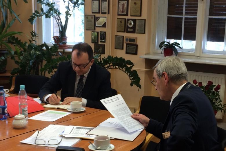 zdjęcie: dwóch mężczyzn siedzi przy stole i przegląda dokumenty