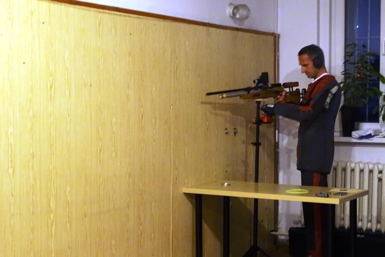 Zdjęcie: mężczyzna mierzy z broni strzeleckiej. Ma słuchawki