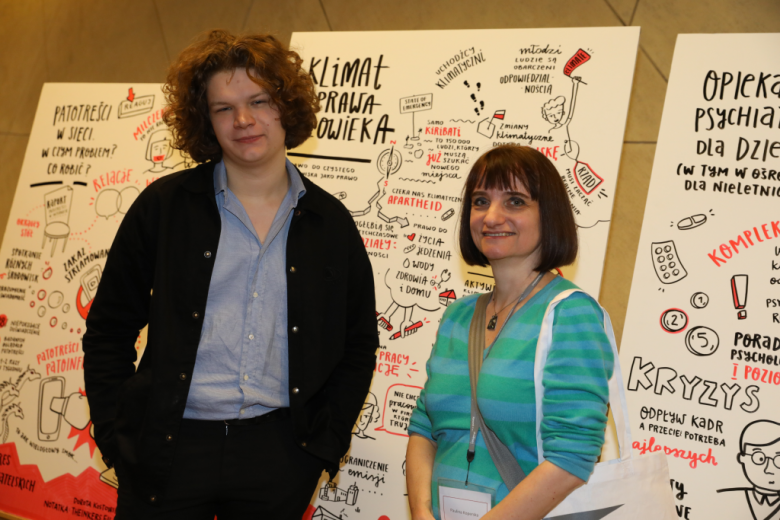 Kobieta i mężczyzna pozują koło grafiki Klimat i prawa człowieka