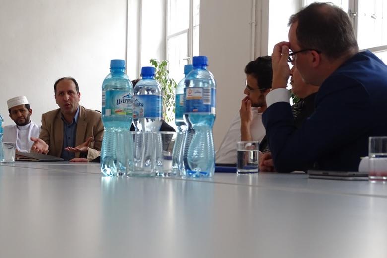Zdjęcie: ludzie przy stole, na którym stoi woda mineralna, w gorącej dyskusji