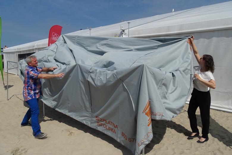 Zdjęcie: ludzie stawiają duży szary namiot z logo RPO